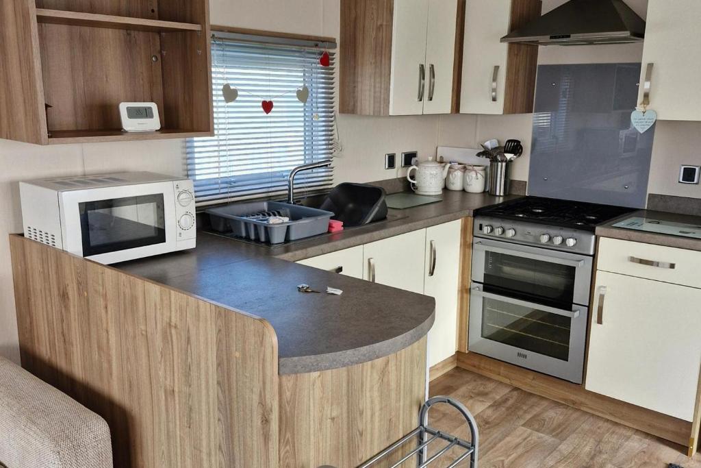 a kitchen with a counter with a microwave and a stove at 3-Bed Caravan - Sleeps 8 - Pool in Skegness