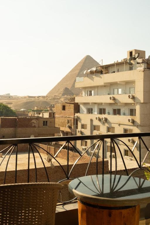 a balcony with a table and pyramid in the background at Jimmy Pyramids Hotel in Cairo