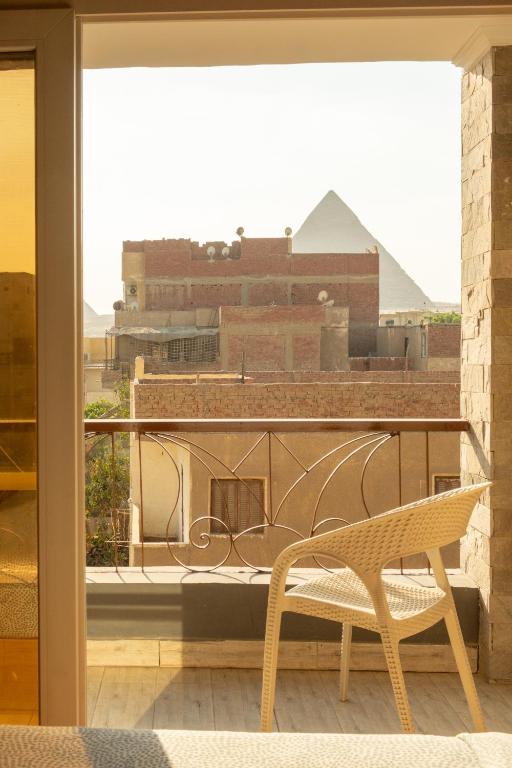 a chair on a balcony with a view of a building at Jimmy Pyramids Hotel in Cairo