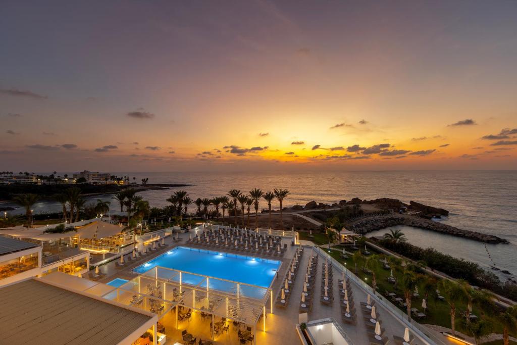 a view of a resort with a pool and the ocean at Queens Bay Hotel in Paphos