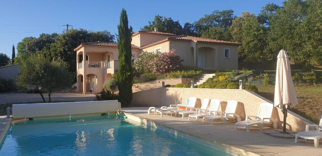 une maison dotée d'une piscine avec des chaises et un parasol dans l'établissement Le MAS DISON, à Euzet