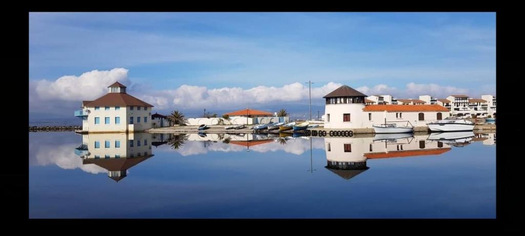Un reflejo de casas y barcos en el agua. en Appartement Cosi Place Martinique, en Le Barcarès