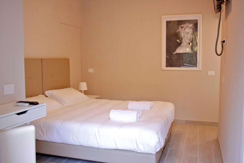 Un dormitorio con una cama blanca y una foto en la pared en B&B Leonardo, en Rho
