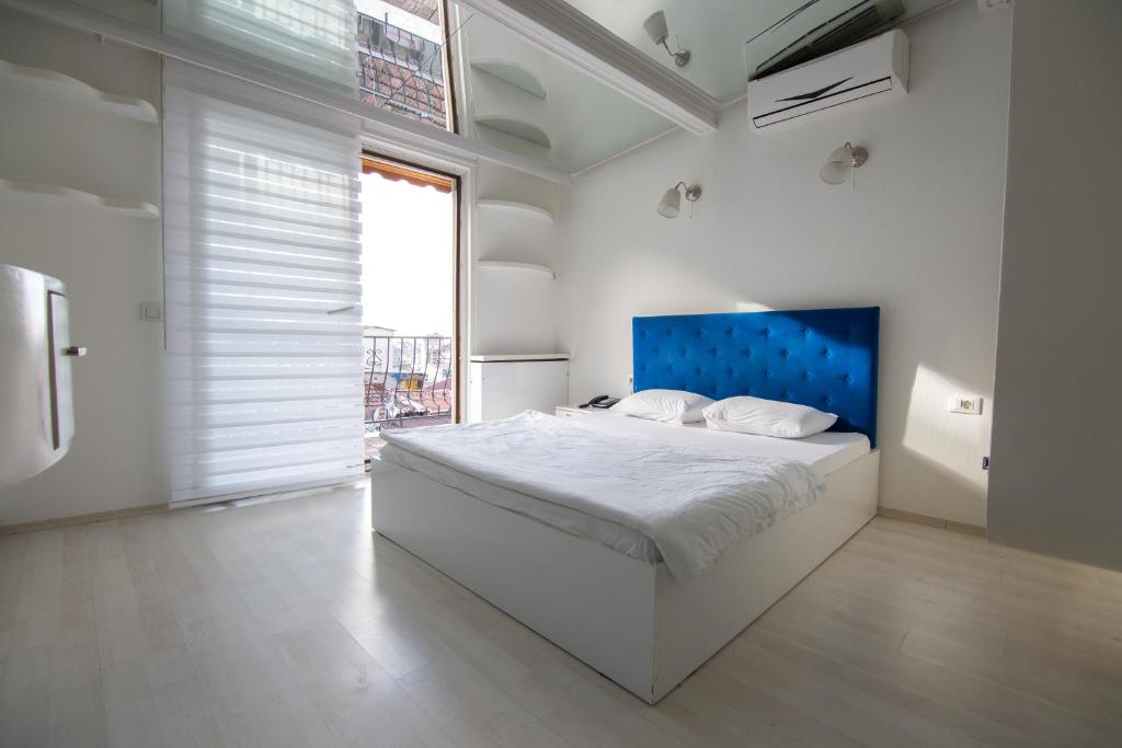 a white bedroom with a large bed with a blue headboard at Element Suites in Istanbul