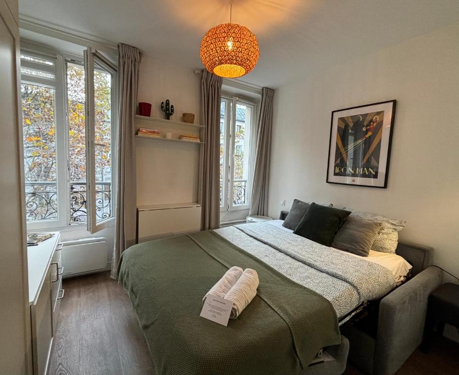 une chambre avec un grand lit et un lustre dans l'établissement Clichy studio Getaway - C70, à Paris