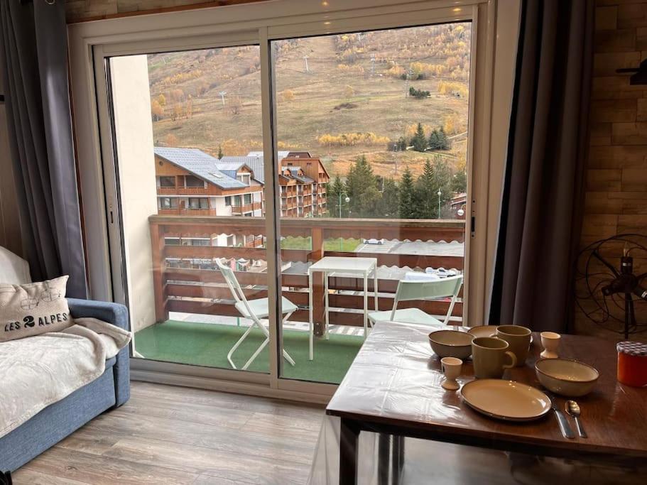 un salon avec une table et une grande fenêtre dans l'établissement Appartement au cœur des 2 Alpes, à Les Deux Alpes