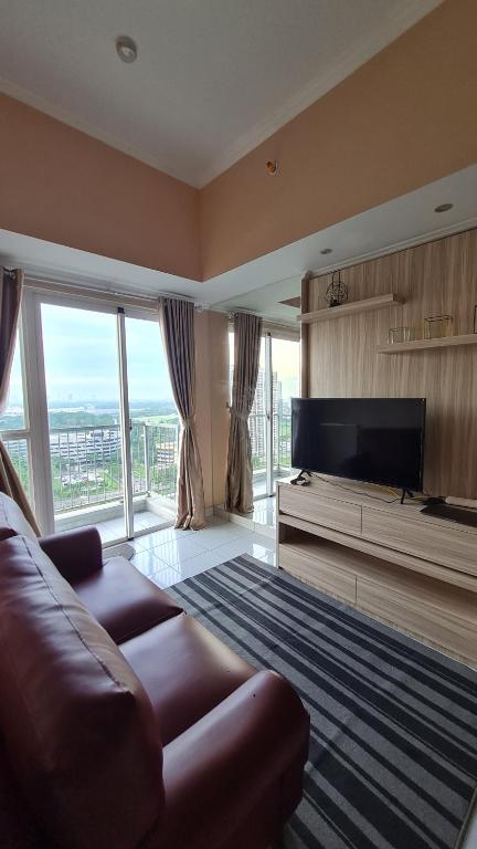 Una sala de estar con un sofá y un televisor de pantalla plana. en 1 BR Apartment at BSD City by Miapato, en Tangerang