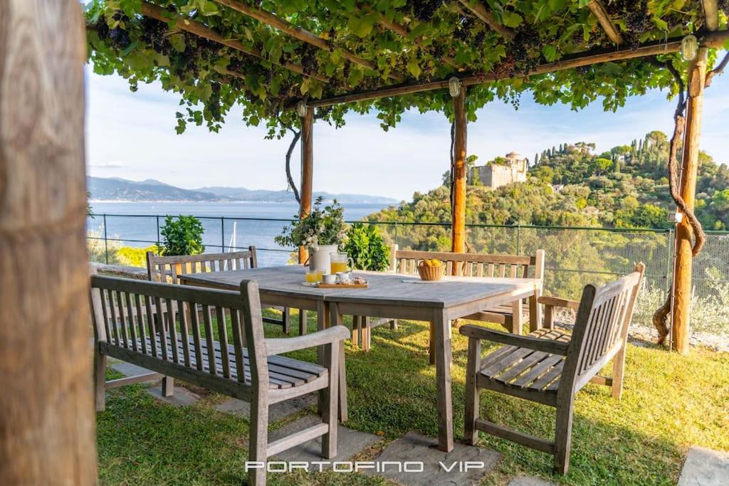 a wooden table and chairs with a view of the ocean at Martino by PortofinoVip in Portofino
