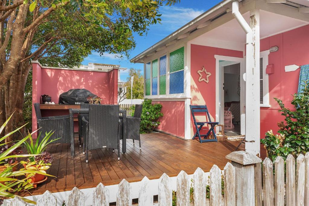 a house with a deck with a table and chairs at Atlantis retro beachside couples retreat in Currarong