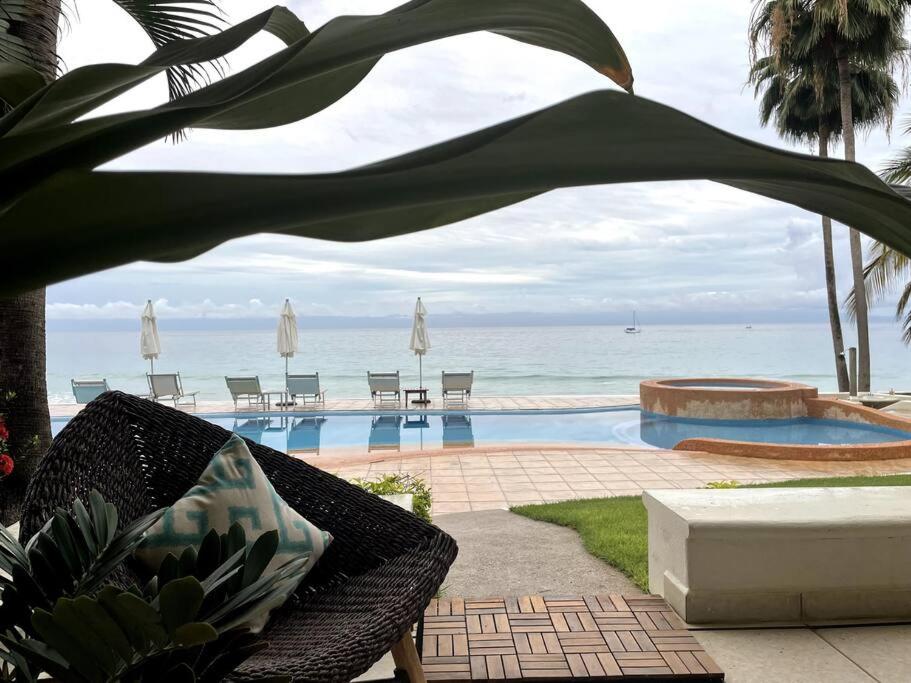 a view of a swimming pool with chairs and the ocean at BEACH GETAWAY! Luxury Beachfront Condo in Punta de Mita! in Punta Mita