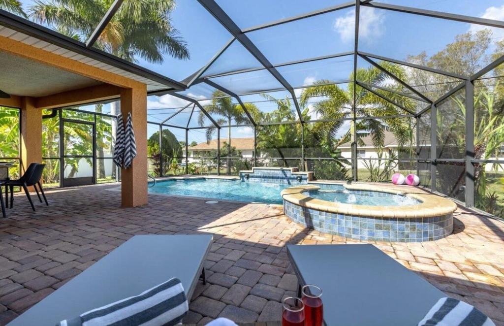 a swimming pool in a glass house with a patio at Tranquil Palms Heated Pool Spa Outdoor TV & More in Cape Coral