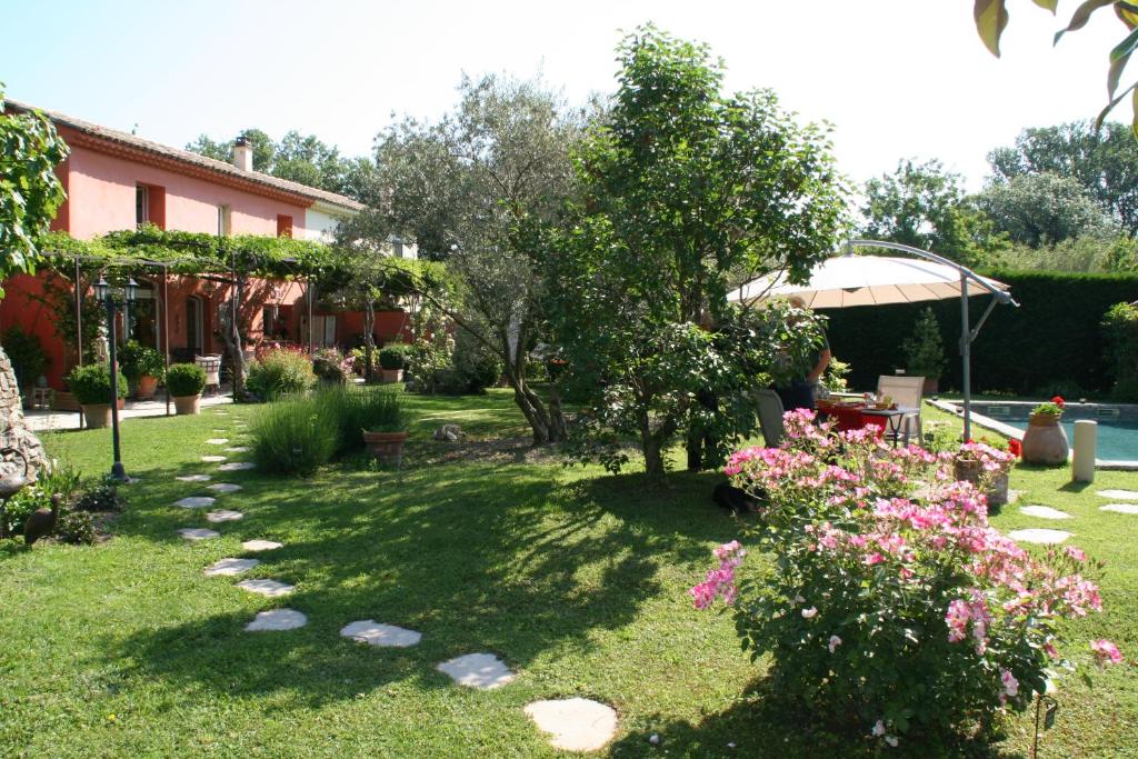 un jardin avec des fleurs roses et une maison dans l'établissement Tybolea, à Cavaillon