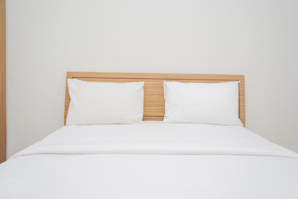 - un lit avec des draps et des oreillers blancs dans l'établissement Relax and Simply Studio Apartment at Parkland Avenue By Travelio, à Tangerang