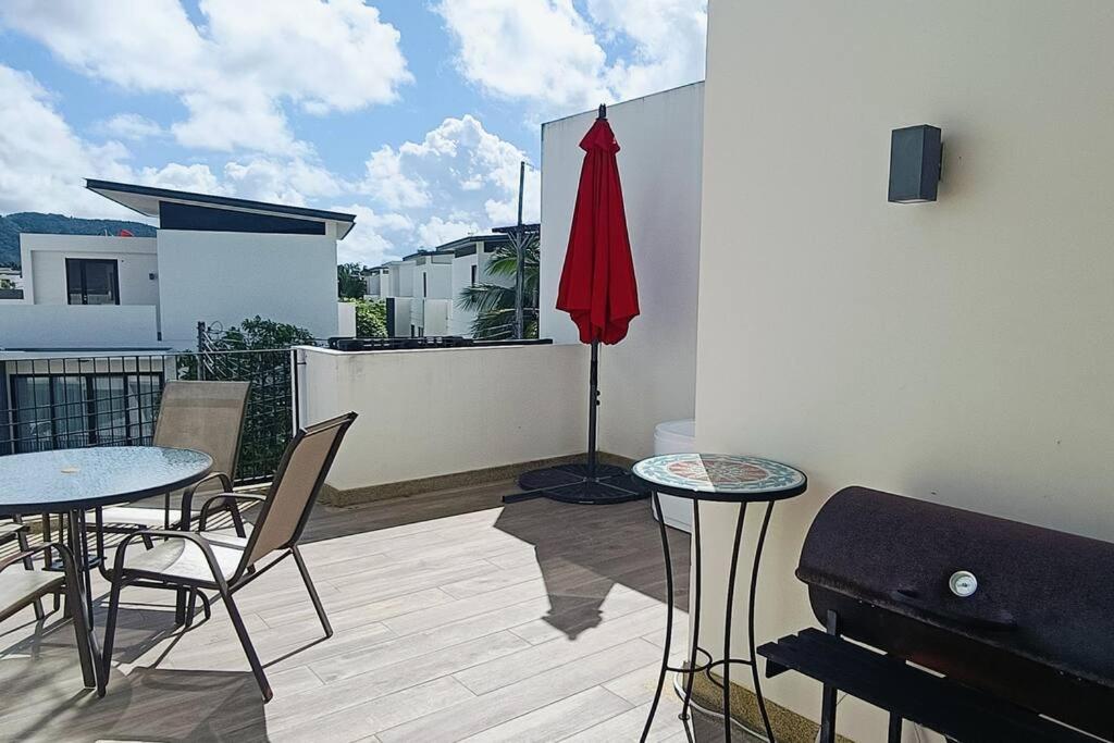 a balcony with two tables and a red umbrella at Bangtao Beach 600m Laguna 3BDR 3,5bath with Jacuzzi and BBQ up to 8 guests 5 nights Free taxi in Phuket