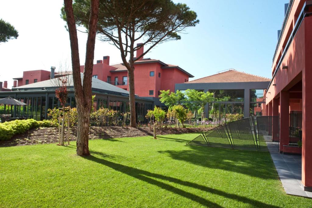 a green yard with a tree and a building at Sheraton Cascais Resort - Hotel & Residences in Cascais
