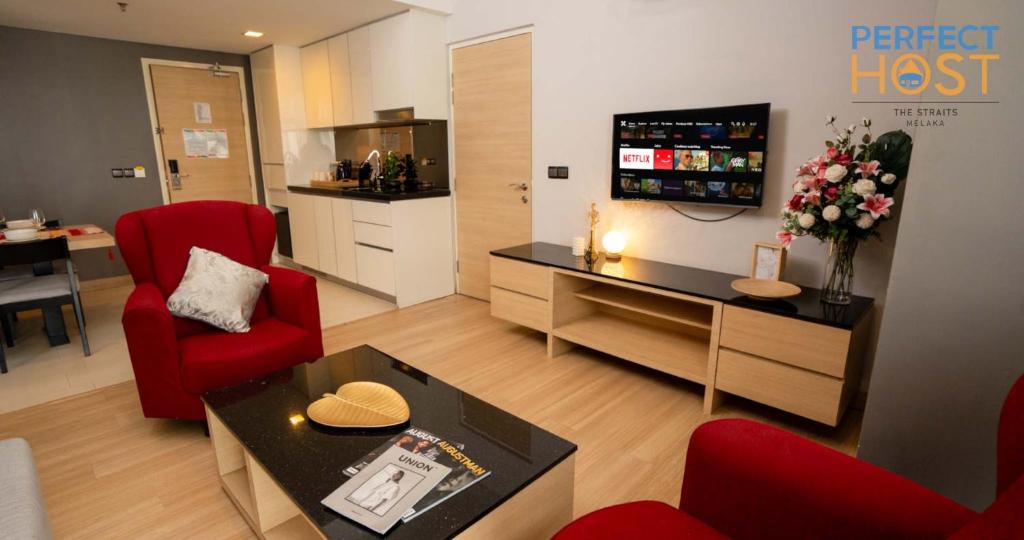 a living room with red chairs and a table at The Straits Melaka by Perfect Host in Malacca
