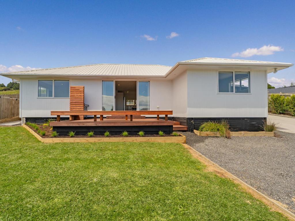 a white house with a bench in the yard at Greenhills Charmer - Coromandel Town Holiday Home in Coromandel Town