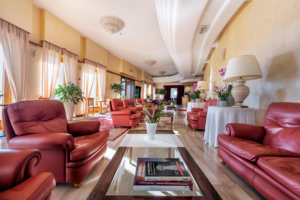 ein Wohnzimmer mit roten Ledersesseln und Tischen in der Unterkunft Astura Palace Hotel in Nettuno