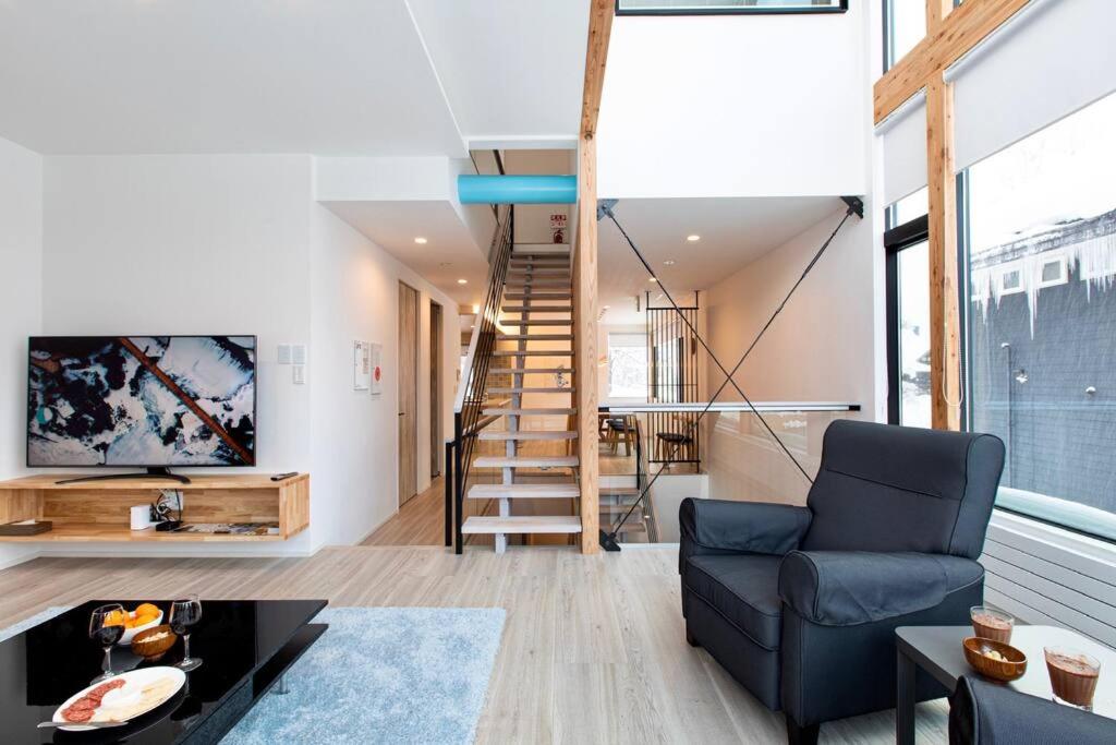 a living room with a blue chair and a staircase at Olaf House in Niseko