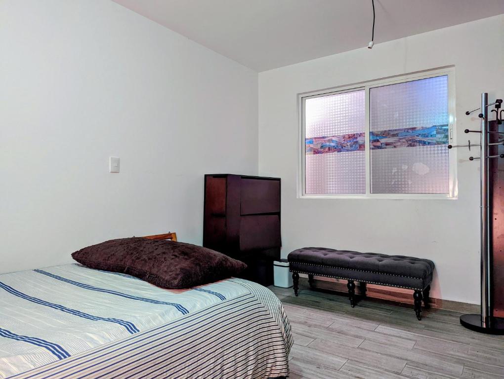 a bedroom with a bed and a bench and a window at Habitación privada totalmente amueblada, CMDX in Mexico City
