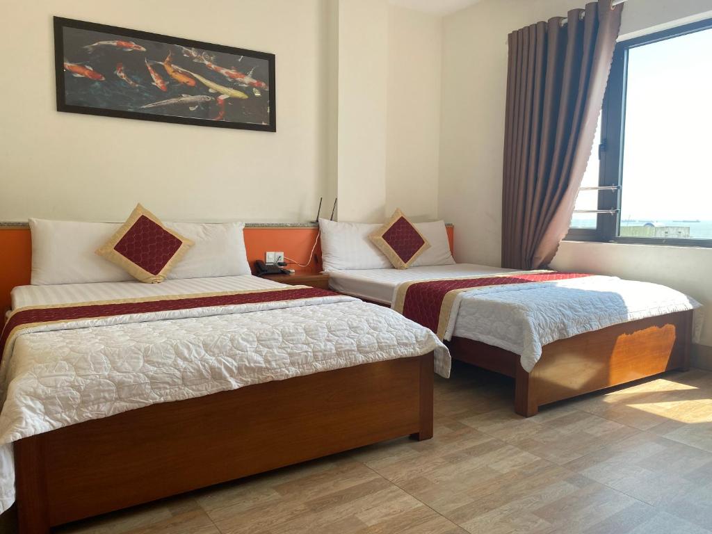 a hotel room with two beds and a window at Hoàng Hưng Hotel in Quy Nhon