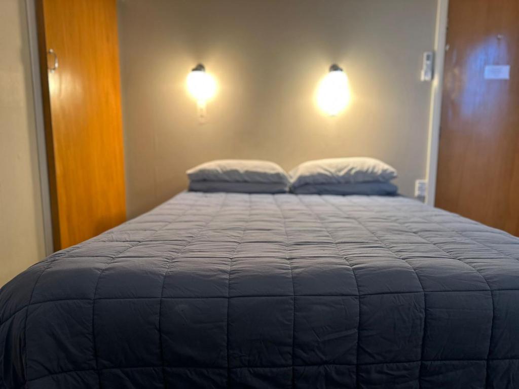 a bed in a room with two pillows on it at Merrylees Budget Hotel in Dannevirke