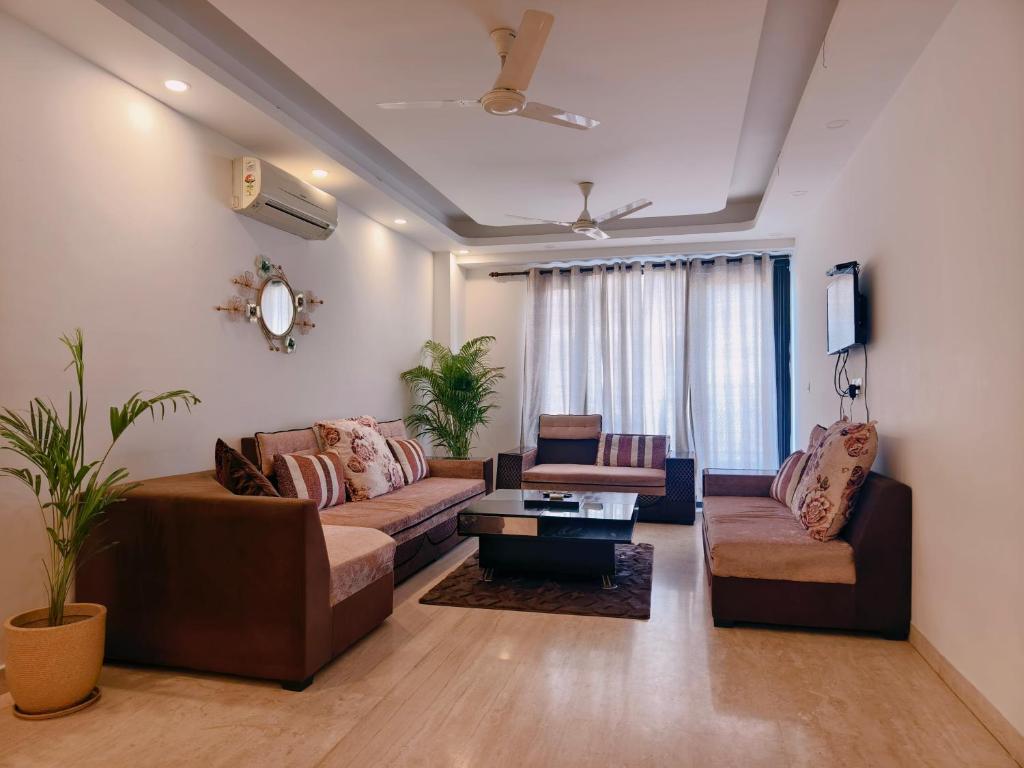a living room with two couches and a tv at Hostmystay- 3Bhk Terrace! Gk1 M block in New Delhi