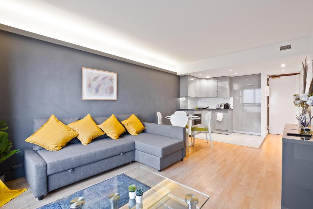 un salon avec un canapé gris et des coussins jaunes dans l'établissement Charmant Appartement Quartier Tour Eiffel Free Netflix, à Paris