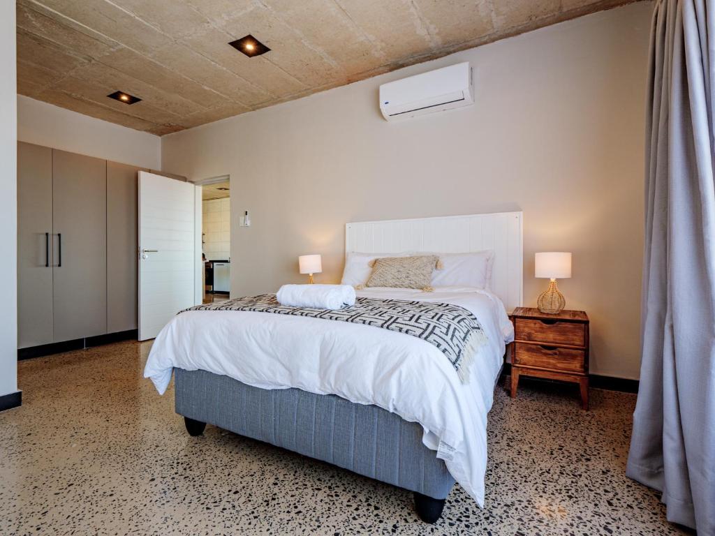 a bedroom with a large bed and two lamps on a table at The Lofts on Manaar in Durban