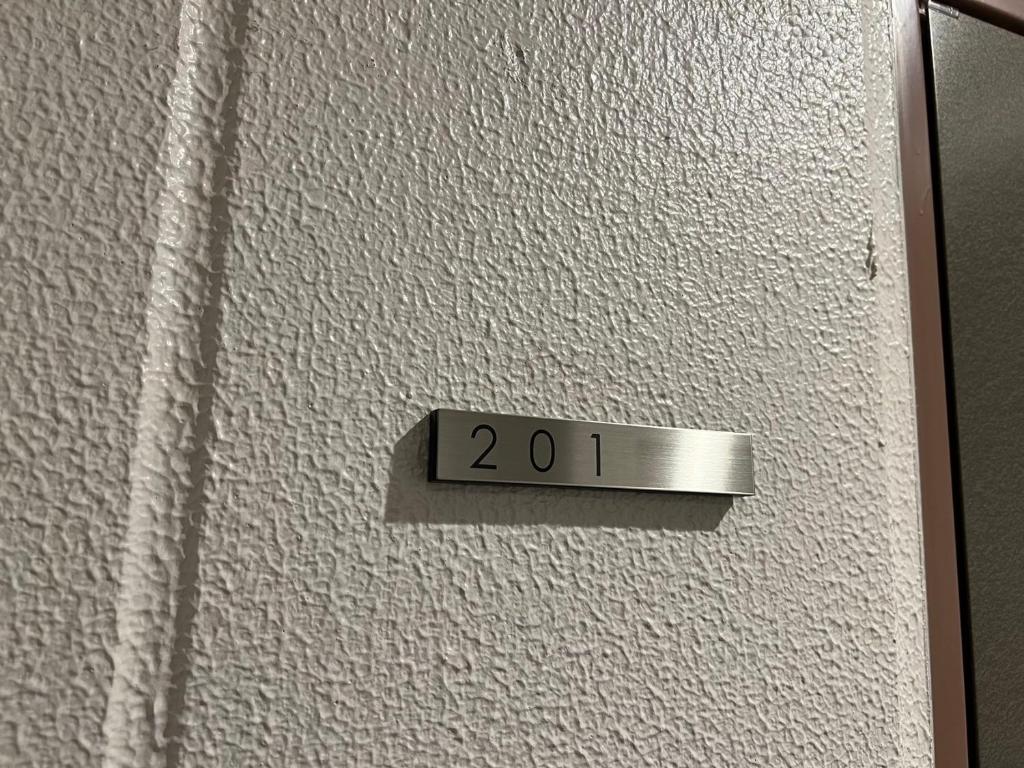 a sign that says on a white wall at SkyHotel Kikukawa 駅徒歩2分 in Tokyo