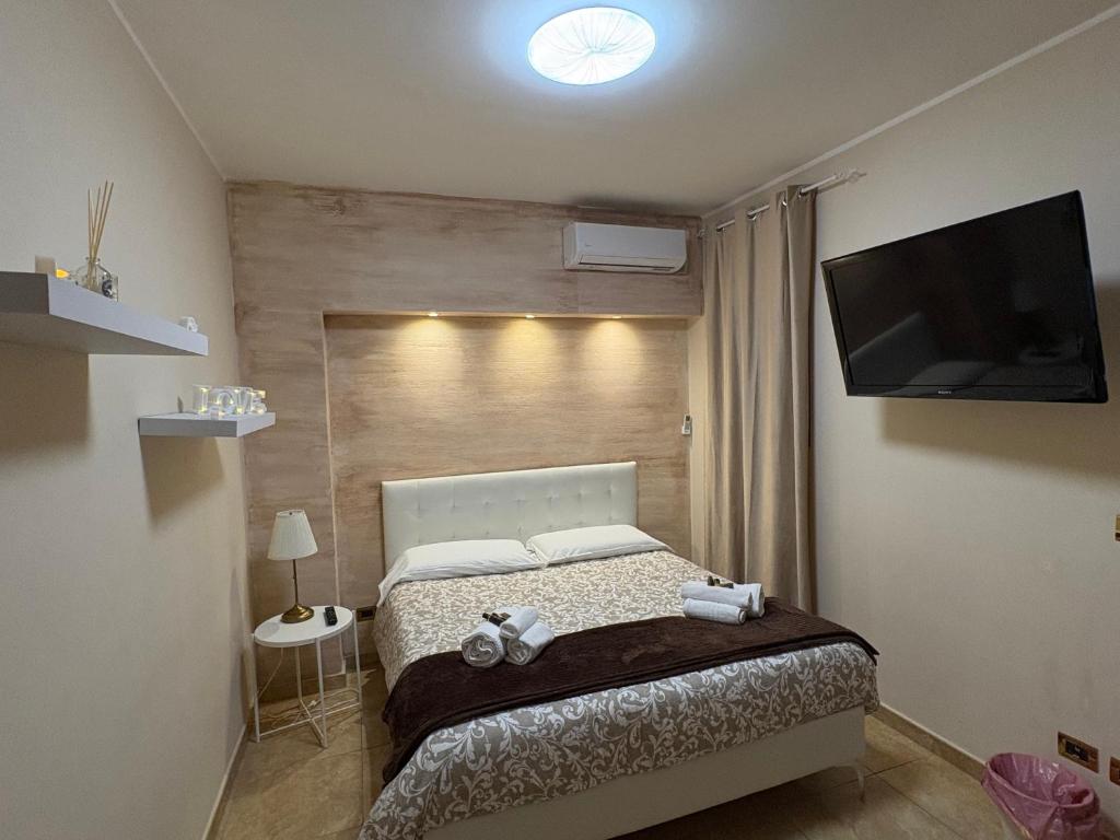 Un dormitorio con una cama y un televisor de pantalla plana. en Wanderlust maison de voyage, en Catania
