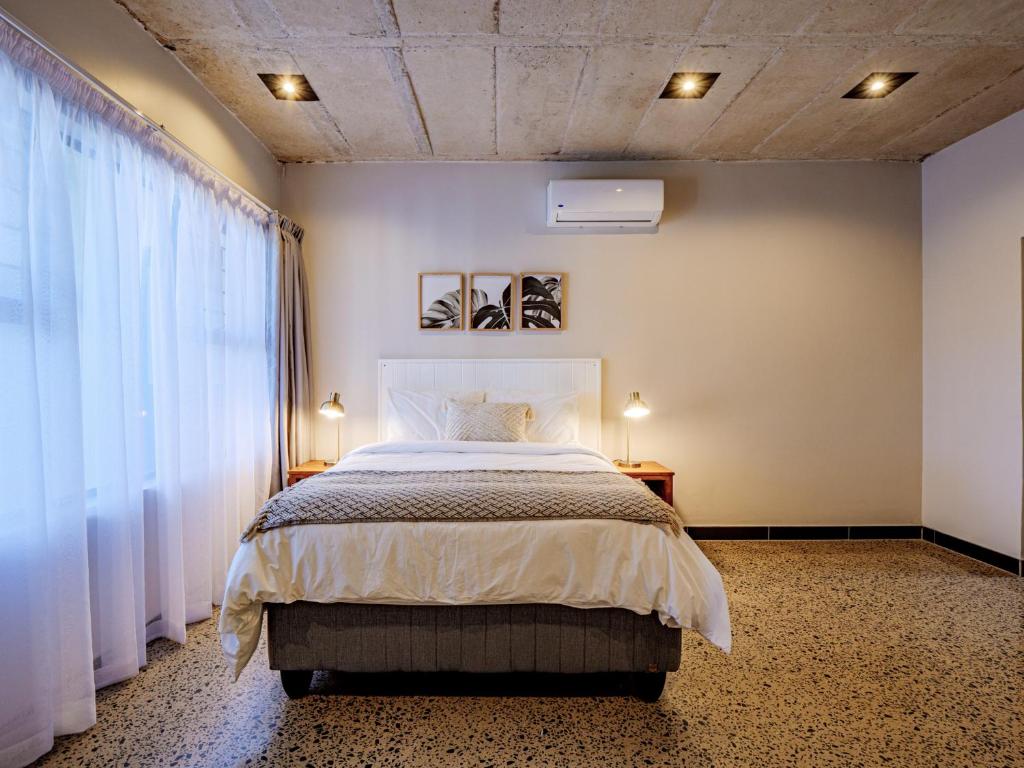 a bedroom with a large bed with white curtains at The Lofts on Manaar in Durban