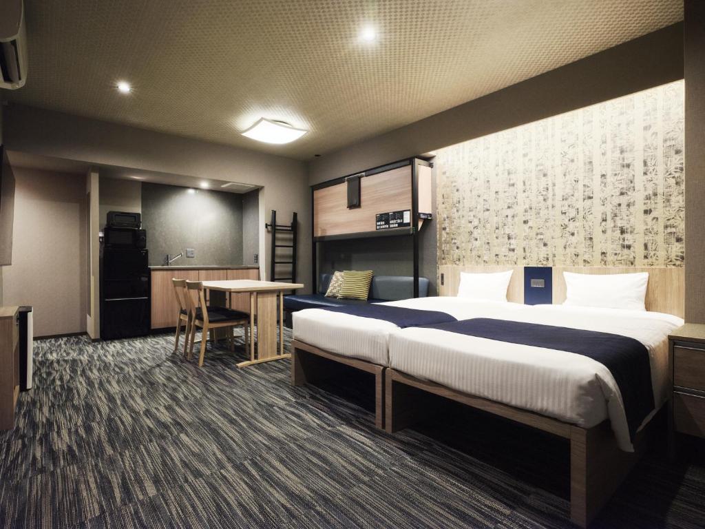 ein Hotelzimmer mit zwei Betten und einer Küche in der Unterkunft MONday Apart Premium AKIHABARA in Tokio