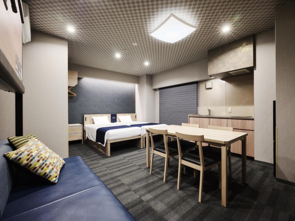 ein Zimmer mit einem Bett, einem Tisch und Stühlen in der Unterkunft MONday Apart Premium UENO OKACHIMACHI in Tokio