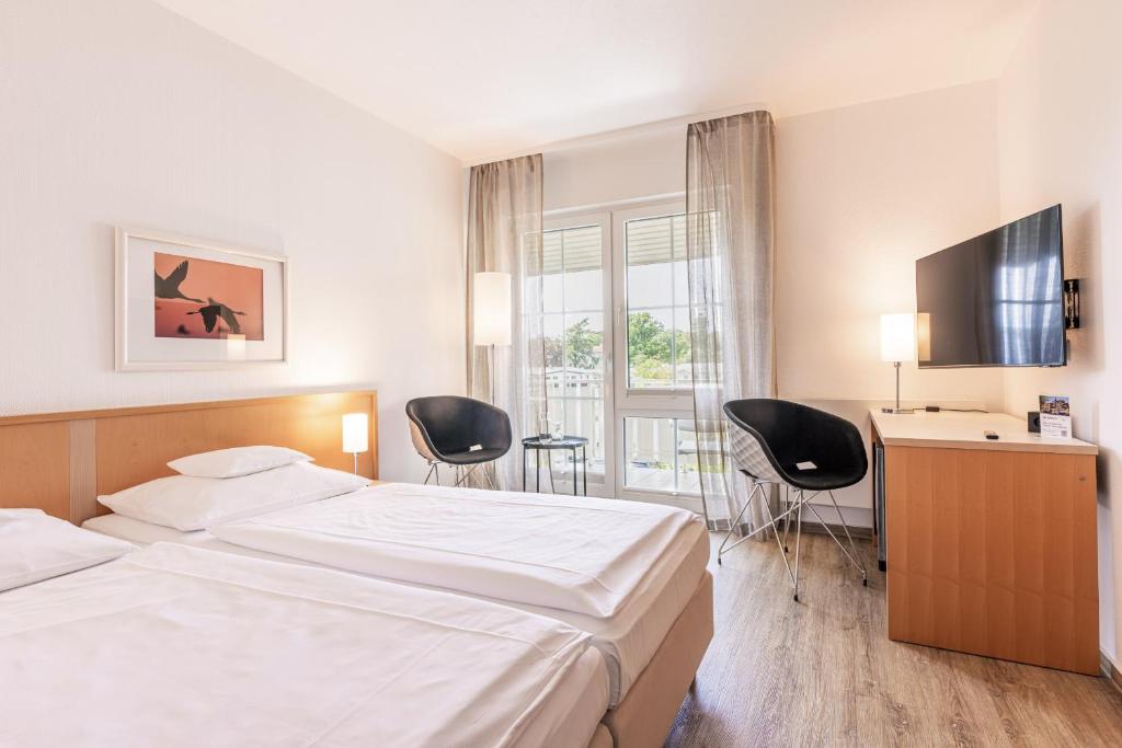a hotel room with a bed and two chairs at Inselhotel Rügen in Göhren