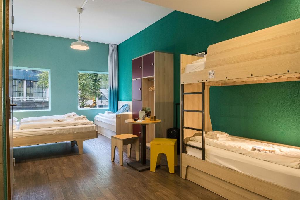 a bedroom with two bunk beds and a green wall at MEININGER Hotel Amsterdam City West in Amsterdam