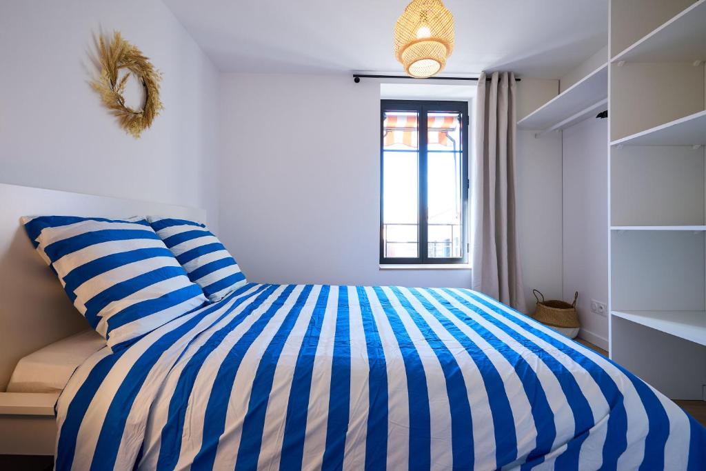 - une chambre avec un lit rayé bleu et blanc dans l'établissement La Villa Orange, à Carcassonne