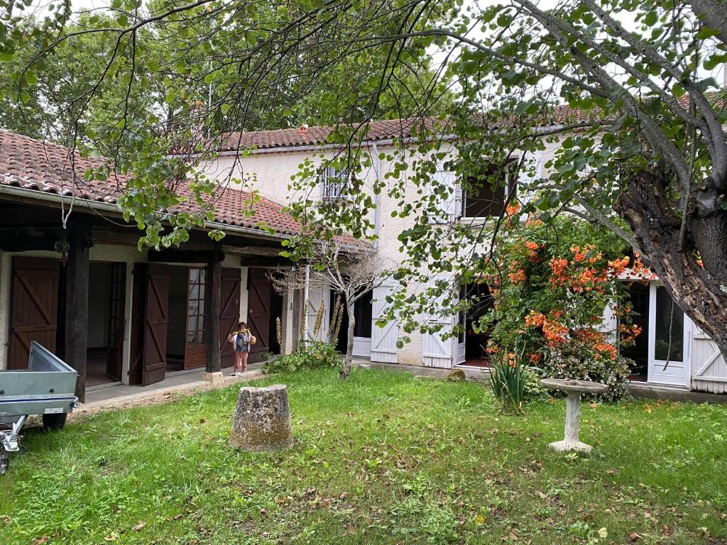 une femme debout devant une maison blanche dans l'établissement Maison Saint Roch, à Mouchan
