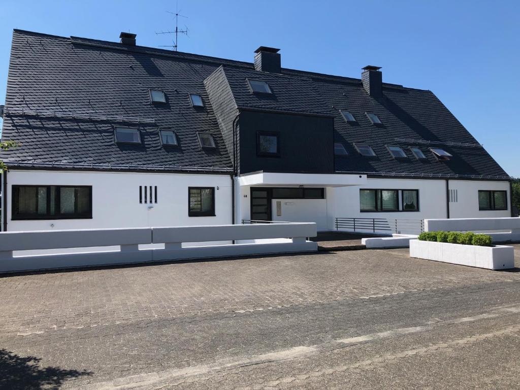 een groot wit gebouw met een zwart dak bij Ferienwohnung Wolkenplatz in Winterberg