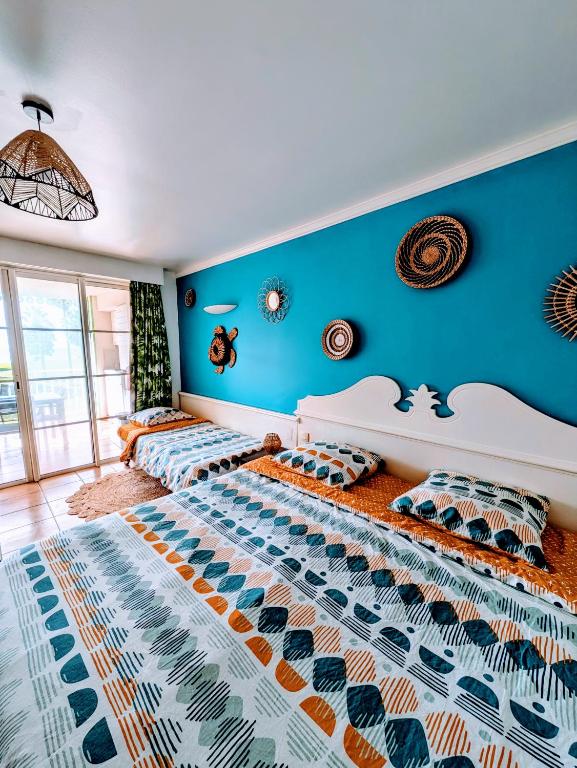 圣吕斯Ti'Karaïb Appartement Vue Mer的一间蓝色墙壁的房间里有两张床