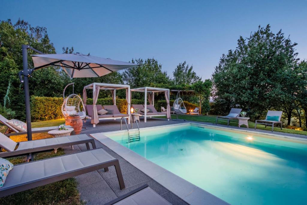 a swimming pool with chairs and an umbrella at Casa Bellavista at Borghetto Farmhouse in San Gennaro