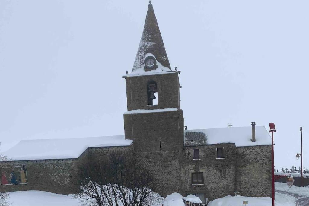 un vieux bâtiment avec une tour d'horloge dans la neige dans l'établissement Duplex au village Bolquere-Pyrénées 2000 ski-été, à Bolquère-Pyrénées 2000