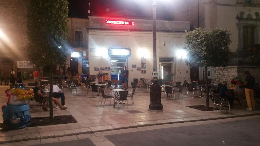un grupo de personas sentadas en sillas fuera de un edificio por la noche en Bar Centrale Zichella, en Lacedonia