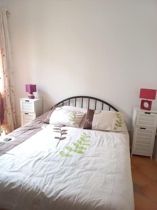 une chambre avec un lit avec des draps blancs et des oreillers dans l'établissement Maison de village calme pour amoureux du vélo, à Bédoin