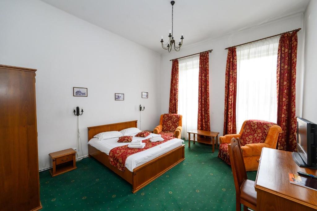 a bedroom with a bed and two chairs and a tv at Hotel Transilvania in Cluj-Napoca