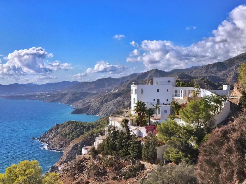 een wit gebouw op een heuvel naast de oceaan bij Castillo de ensueño in La Herradura