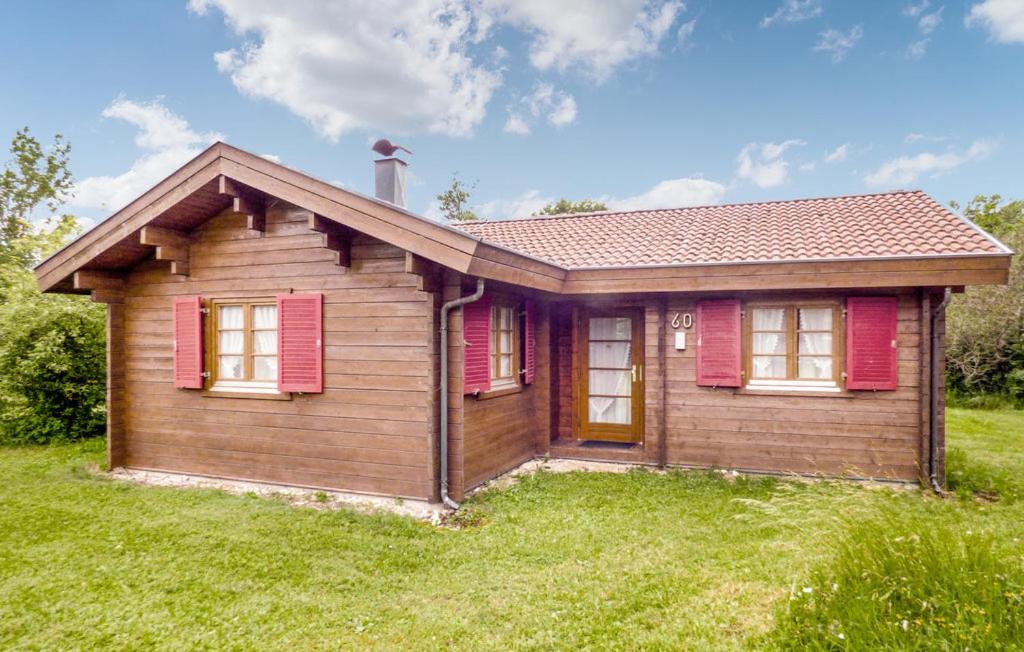 a small house with red shutters on a green field at Ferienhaus Tauber 60 in Hayingen