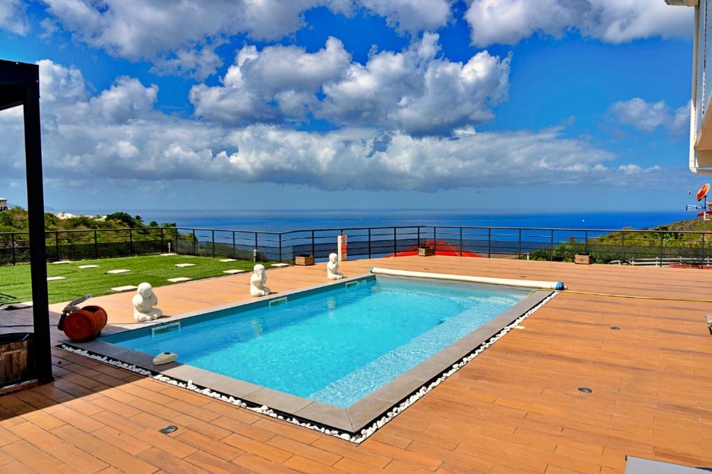 a swimming pool on a patio with the ocean in the background at Magnifique appartement Wonm Vue mer & pisicine in Case-Pilote