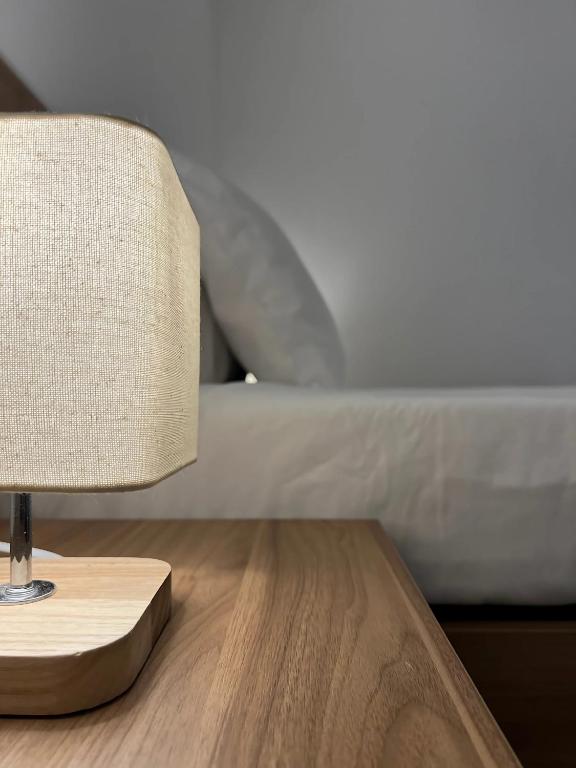 a lamp on a wooden table next to a bed at Floriana Cosy Corner in Il-Furjana