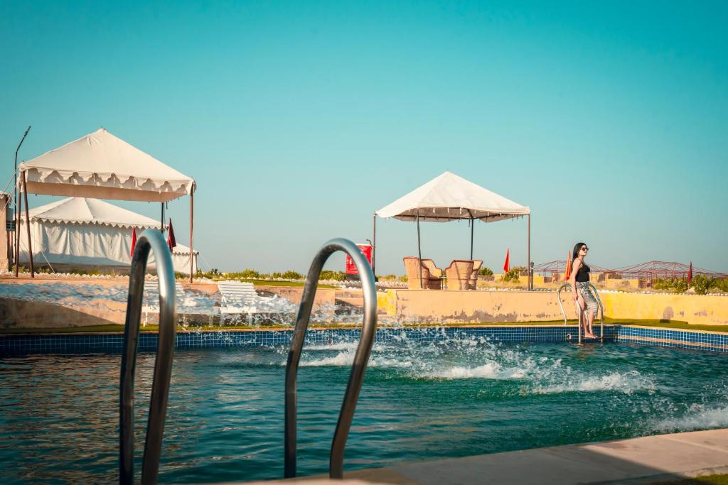 a woman is standing in the water at a swimming pool at Surya-Ansh Desert Wellness Resort in Chhilro